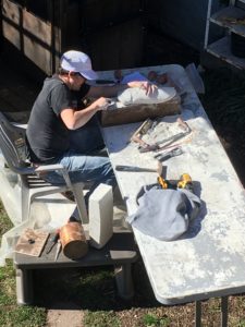 A block of plaster, a pile of tools and an artist carving a cicada.